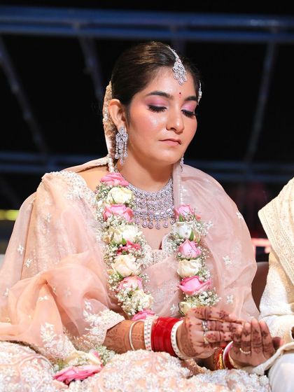 The bride participates in a wedding ritual, her hands held in prayer.