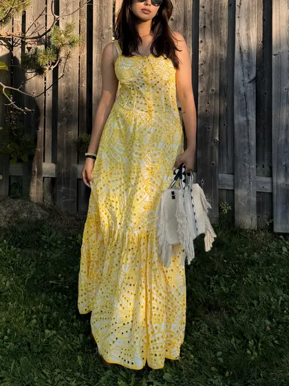 A full-length shot showing the entire yellow dress and a stylish white bag.