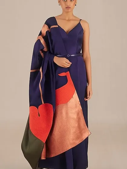 A modern take on the saree. This navy blue gown with a dramatic, artistic drape is for the woman who loves to blend tradition with high fashion.