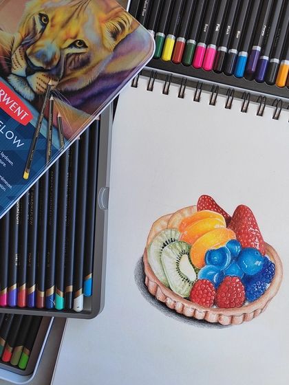 The fruit tart drawing in my sketchbook, next to the tin of Derwent Chromaflow pencils used to create it.
