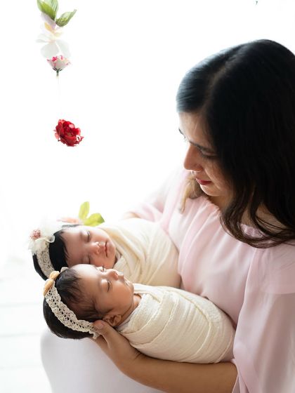 A close-up of a mother holding her sleeping twin babies. You can feel the overwhelming love and tenderness in this quiet moment.