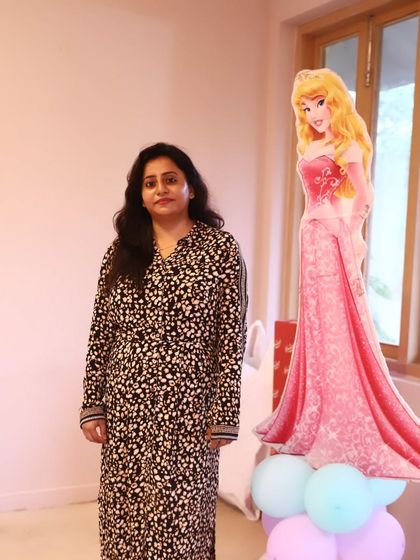 A guest posing with a princess cut-out, part of the interactive decor for a children's party.