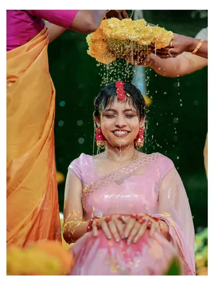 The pure joy of a Haldi ceremony. This moment, with the bride being showered in water and marigold petals, perfectly captures the fun and vibrant spirit of this pre-wedding ritual.