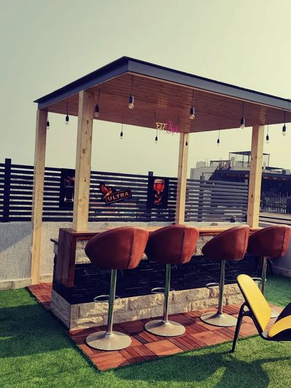 After: The finished rooftop bar, complete with a pinewood-clad pergola, bar stools, and ample green space for entertaining.