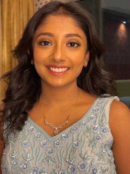 A close-up of a simple and fresh party makeup look. The focus is on clean skin, a subtle winged liner, and a bright, genuine smile.