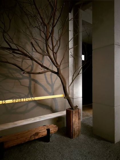 "Art is Spiritual." This corner of the studio features an installation that is a core part of our philosophy. A preserved tree branch casts a shadow on the wall, merging with the engraved quote to create a powerful statement about the soul of our work.