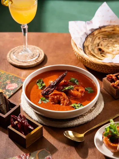 A rich and spicy prawn curry. The deep red color of the gravy and the fresh herbs make it look incredibly flavorful.