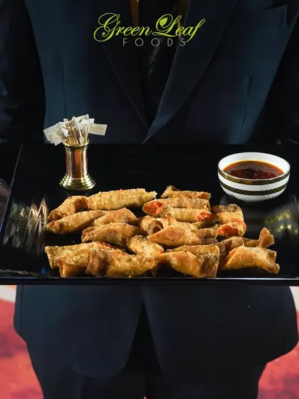 Our crispy fried wontons are a delicious bite-sized appetizer. Served on a sleek black platter with a dipping sauce, they showcase our expertise in Asian cuisine.