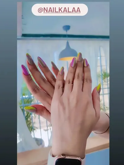 A unique and colorful set of long stiletto nails with a multi-chrome finish that shifts between pink, yellow, and green.