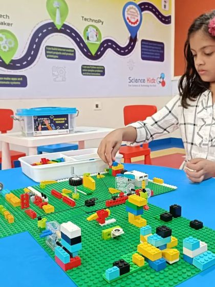 A young student concentrates on her intricate LEGO creation. Building with LEGOs helps children learn to think in three dimensions, solve structural problems, and patiently work towards a finished product.