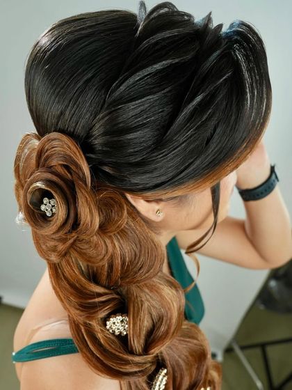 A top-down view of an intricate braided hairstyle, featuring a floral bun made from hair and cascading waves.