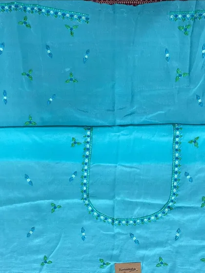 An unstitched blouse piece in a lovely shade of blue, with delicate floral butis embroidered all over. The neckline is also marked out with a simple, elegant border stitch.