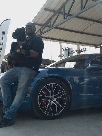 A different angle of me holding my dog by the blue Porsche. He is completely relaxed in my arms.
