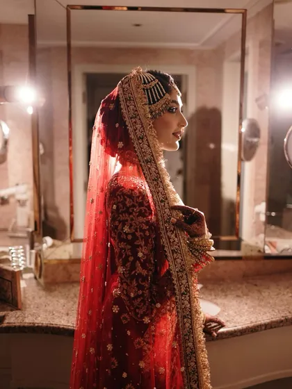 A stunning profile of the bride, with dramatic lighting highlighting her silhouette and the intricate details of her traditional headwear and gown.