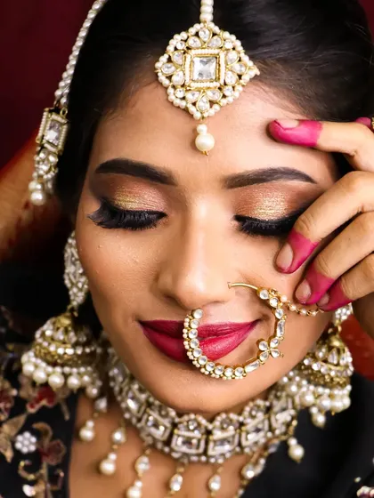 A soft bridal glam look with golden glitter eyes and a bold red lip. This close-up shows the beautiful texture of the eyeshadow and the precision of the lip application.