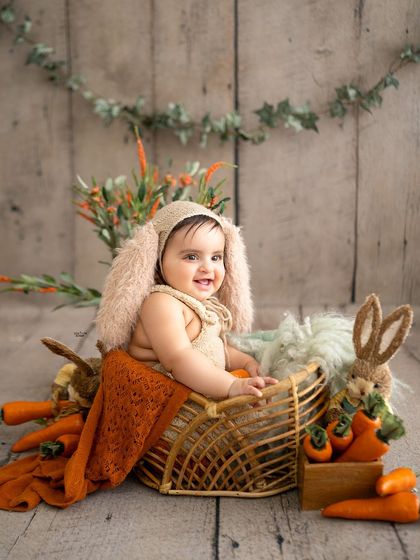 A happy bunny in a basket, surrounded by carrots.