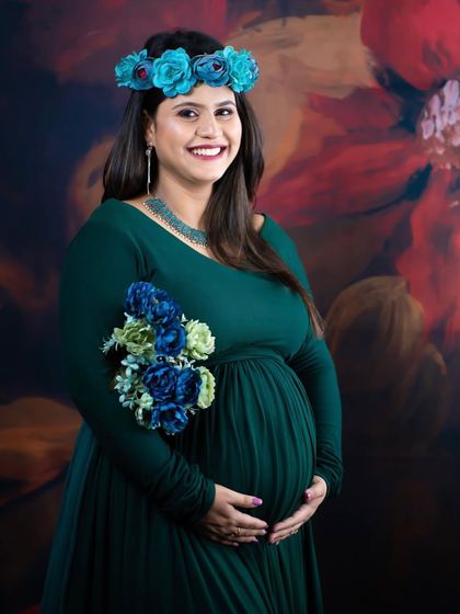 A happy and smiling portrait of a mom-to-be in a green gown, holding a matching bouquet of flowers. The floral crown completes this fresh and natural look.