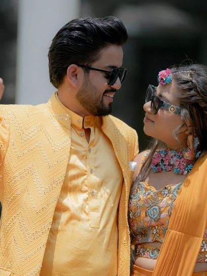 A cool, candid shot of Nikhil and Srishti at their Haldi, with a selective color effect that makes their yellow outfits pop against a monochrome background.