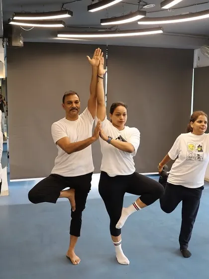 A group of members holding a balancing yoga pose, showing the collective focus and energy of the class.