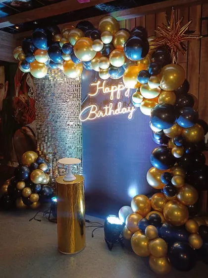 A classic and bold look for a 40th birthday. The deep blue and gold chrome balloon arch creates a dramatic entrance, perfectly complemented by a simple "Happy Birthday" neon sign.