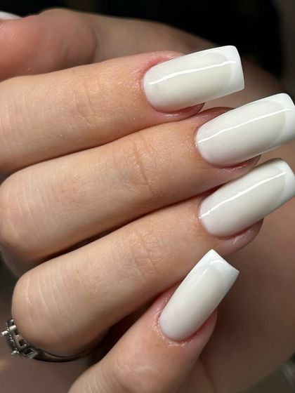 A modern take on the French manicure with a milky white overlay on long, square-shaped extensions. This creates a soft, blended look instead of a harsh line.
