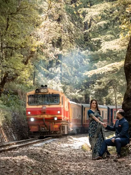 The iconic Shimla toy train passes by as the couple shares a quiet moment, blending history and romance. This shot captures the timeless charm of a classic Himalayan pre-wedding photoshoot.