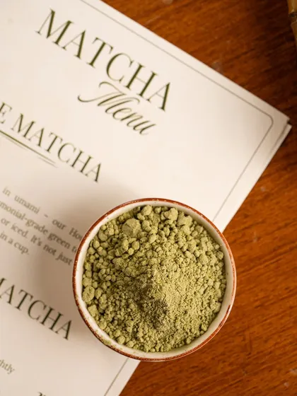 A simple, clean shot of high-quality matcha powder next to the menu, signaling the authenticity of the ingredients.