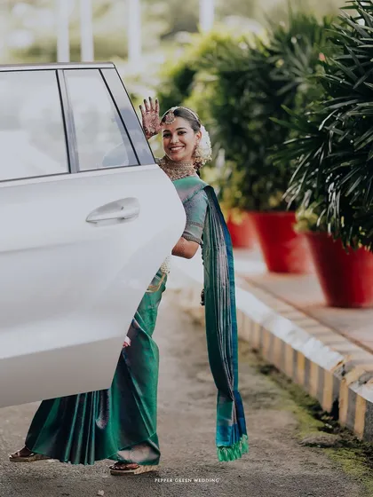 A fun and playful shot of the bride waving goodbye as she gets into the car, a happy end to the celebration.