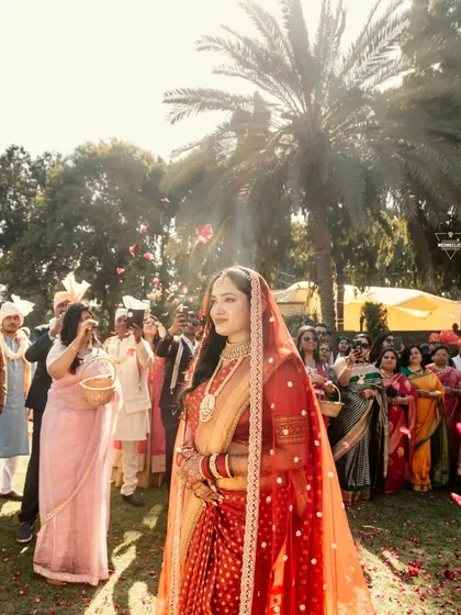 The bride's solo walk down the aisle, surrounded by guests and a shower of flower petals, her expression serene and happy.