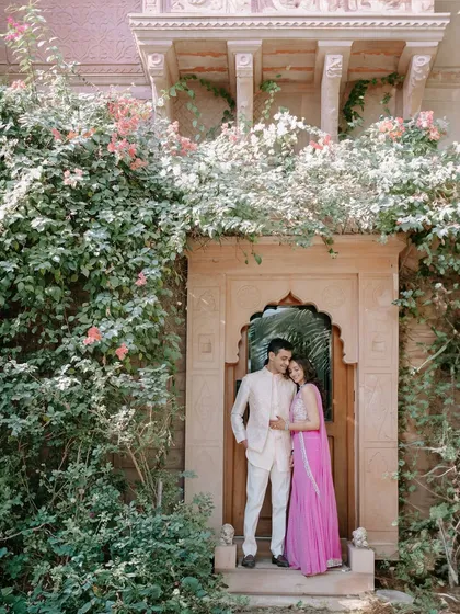Kanav and Saloni framed within a beautiful arched doorway covered in flowering vines. This shot perfectly combines the grandeur of the location with a touch of natural romance.