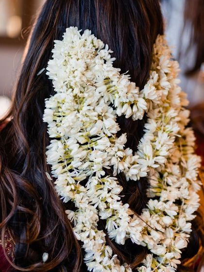 The fragrant white 'Mallige Gajaras' in the bride's hair are a beautiful and essential part of the look. The scent and sight of fresh flowers add a layer of sensory beauty to the day.