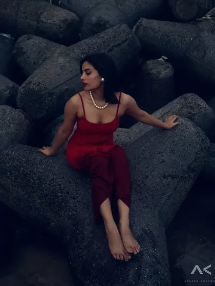 A collection of portraits featuring a model in a red dress on the rocks and by the water. The series explores different poses and moods, from serene to powerful.