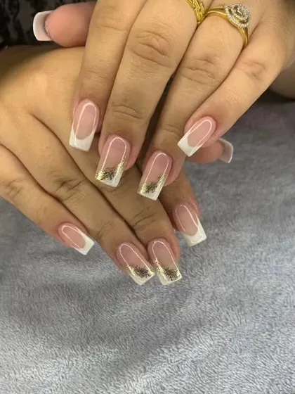 A classic French manicure on square nails with encapsulated gold flakes at the tips.