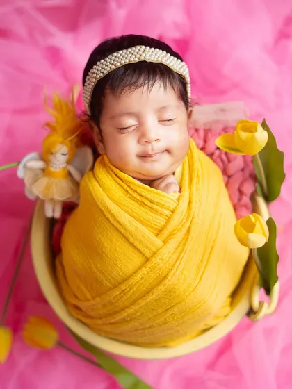 A sweet, sleepy smile from this little ray of sunshine. Wrapped in bright yellow, this newborn looks so content and happy.