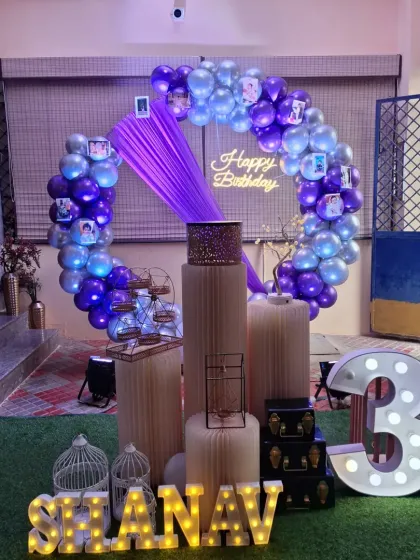 The purple draping and photos clipped to the balloon ring add a personal and charming touch to this home birthday setup.