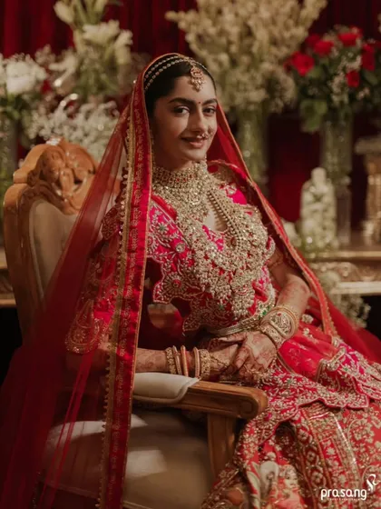 A portrait of bridal grace. Seated in a classic ornate chair, the bride's smile radiates happiness. My planning includes selecting furniture and decor that enhance the royal aesthetic of the event.