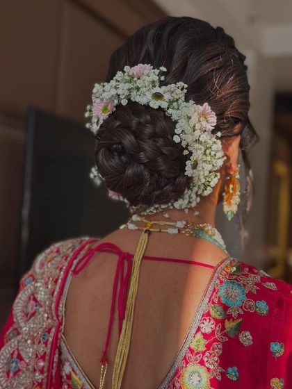 This braided bun is beautifully decorated with a mix of baby's breath and delicate daisies. The pop of pink from the daisies adds a lovely, fresh touch.