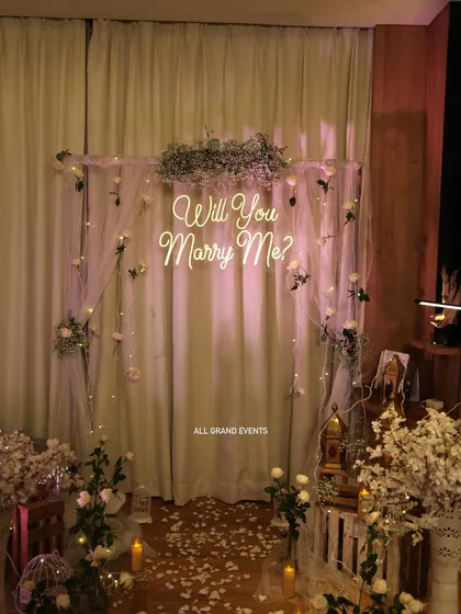 A full view of our indoor proposal decoration package. We use a stand with sheer curtains, fairy lights, and floral arrangements to create a dedicated, photo-ready spot within any room.
