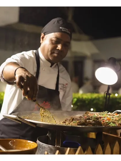 A chef manages a live tawa station, cooking up flavourful Indian specialties. The sizzling pan and aromatic ingredients create an irresistible draw for guests.