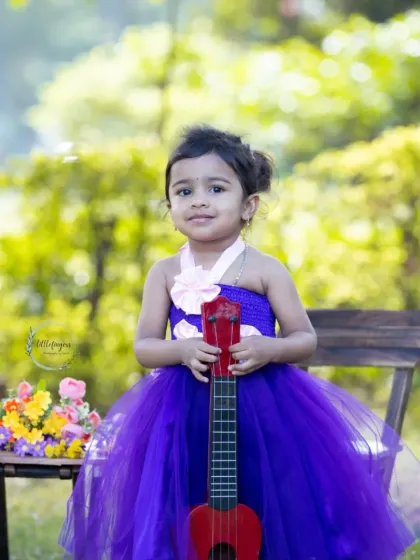 A sweet portrait of a little girl in a purple dress, holding her toy guitar.