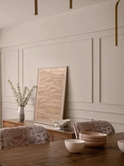 A detail of the dining area in "Apartment 222," focusing on the custom sideboard and the textured artwork leaning against the wall. The combination of wood, fabric, and art creates a space that is both functional and beautiful.
