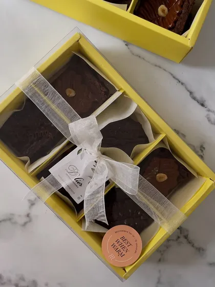 Our box of six fudgy, eggless brownies, featuring both classic chocolate and hazelnut flavors. Made with premium couverture chocolate, they are best enjoyed warm. The clear-lid box and elegant ribbon make it a perfect ready-to-gift treat.