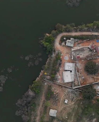 A top-down drone shot showing the Himayatsagar Lakehouse site's relationship to the water's edge.
