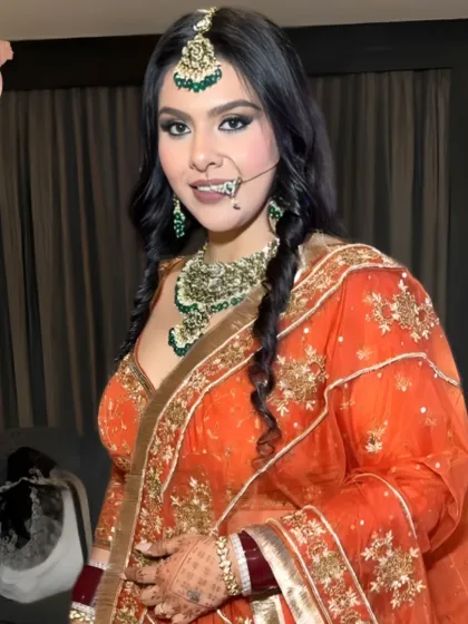 A full-length view of the reception look, showing the beautiful orange lehenga and the braided hairstyle.