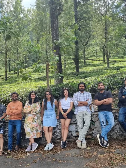 The group taking a casual break against a backdrop of tall trees during our Valparai exploration. It's these relaxed moments that build friendships.