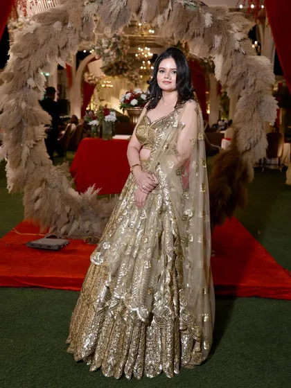 A full-length shot of the guest in her golden lehenga, posing against a beautiful wedding decor backdrop.