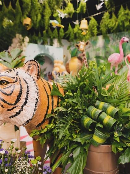 A close-up of the tiger prop from Eshaan's safari, beautifully integrated with faux ferns and purple flowers, showing the artistry in every detail.