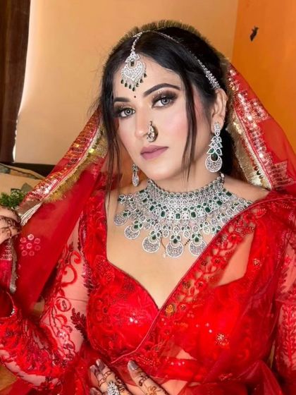 A bride in a red sequin lehenga wearing an American Diamond and emerald necklace set. This piece adds a touch of color and a lot of sparkle.