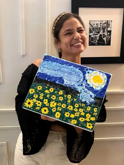 The pure joy of finishing your own masterpiece. This participant is beaming with her completed 'Starry Night' inspired painting, full of texture and life.