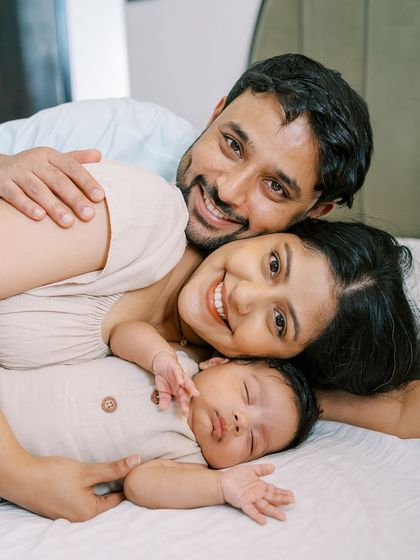 A family lying on the bed, happy and relaxed. Newborn lifestyle sessions are all about capturing the bond between parents and their new baby.
